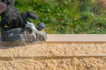 man planing boards with electric tools, chips flying in all directions. Construction, wood processing
