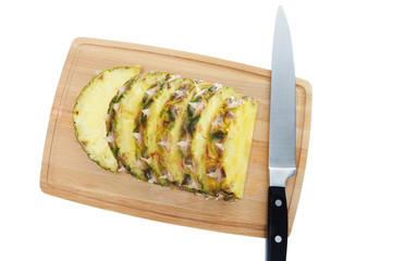 Fresh pineapple slices on brown chopping board.