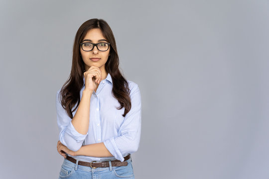 Serious Thoughtful Doubtful Indian Young Business Woman Wear Glasses Hold Hand On Chin Look At Camera Isolated On Grey Studio Background, Confident Hindu Lady Student Professional Portrait