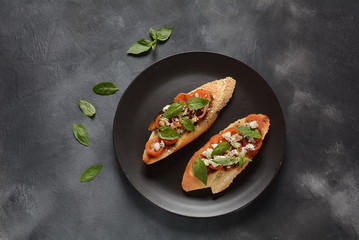 Caprese bruschetta toasts with cherry tomatoes, mozzarella and basil. Appetizers with Italian antipasti snacks.
