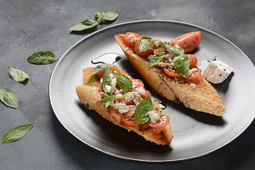 Caprese bruschetta toasts with cherry tomatoes, mozzarella and basil. Appetizers with Italian antipasti snacks