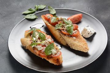Caprese bruschetta toasts with cherry tomatoes, mozzarella and basil. Appetizers with Italian antipasti snacks.