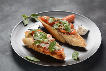 Caprese bruschetta toasts with cherry tomatoes, mozzarella and basil. Appetizers with Italian antipasti snacks. 