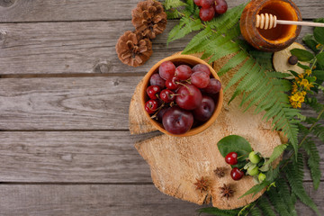 Harvest ripe fruit. Background with fern leaves, red plums and grapes. Vintage on aged wood with copy space. Layout for seasonal offers, top view.
