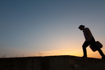 silhouette of man with suitcase at sunrise