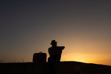 silhouette of man with suitcase at sunrise