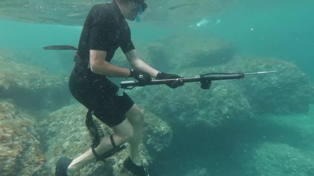 Spearfisher loading harpoon at shallow crystal clear water in the mediterranean sea