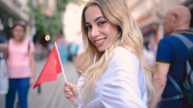 Attractive young beautiful girl waves Turkish flag and pulls arm of her boyfriend at narrow street in Istanbul,Turkey