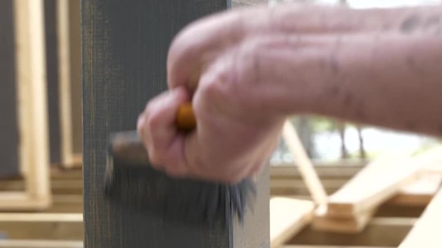 male hand painting a house in dark grey prime color