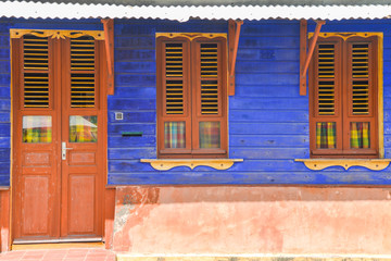 typical house of Martinique with flashy colors blue wall and brown door - obrazy, fototapety, plakaty