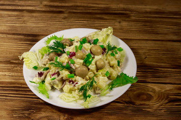 Potato salad with marinated mushrooms, eggs, red onion and mayonnaise on wooden table