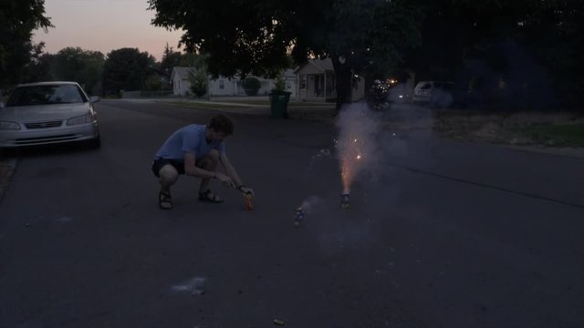 Super Slomo pan of man lighting several fountain fireworks and then getting scared from a flare