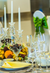 Valentines party dinner table setting with tableware and silverware and glasses set and Candlestick and flower in restaurant.