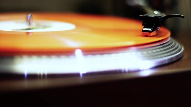 Orange lp vinyl record spinning on retro turntable record player in stereo.