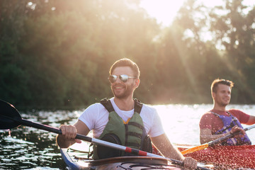 Happy best friends having fun on a kayaks. Kayaking on the river. Two friends in a boat sailing in...