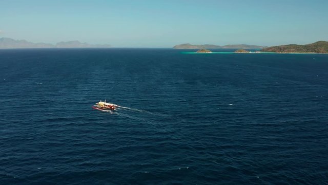 Aerial view tour boat in sea. Seascape blue sea and tropical islands. traditional Filipino wooden outrigger boat called a banca . Motorboat crossing ocean. Banca boat in the Philippines Palawan