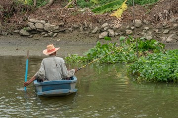 Old man fishing on a boat in the river in Nonthaburi, Thailand. June 28 2019