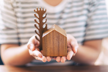 A woman holding a small wooden house and tree model