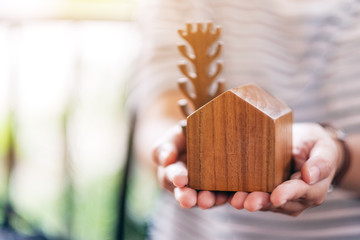 A woman holding a small wooden house and tree model