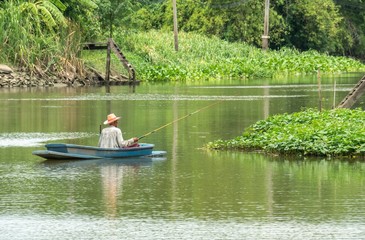 Old man fishing on a boat in the river in Nonthaburi, Thailand. June 28 2019