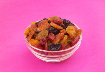 Raisins in glass bowl on pink background