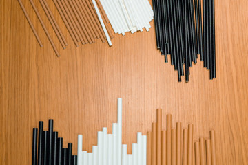 Bundle of paper straws white, brown and black in a wood table display background, great for environmental purpose