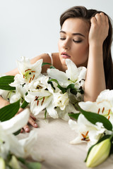 Obraz na płótnie Canvas tender young woman near white lilies isolated on white