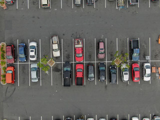 Aerial top view of parking lot at supermarket with with varieties of colored vehicles. People...