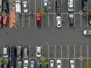 Aerial top view of parking lot at supermarket with with varieties of colored vehicles. People...