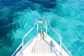 Fototapeta premium (Selective focus) Stunning view of a bow of a yacht sailing on a beautiful turquoise and transparent sea. (Emerald Coast) Sardinia, Italy.