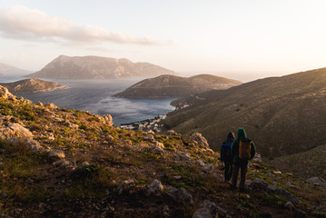 Two people hiking down a hill during sunset in Kalymnos, Greece. 