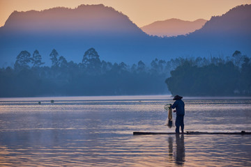 Silhouette of man on lake at sunrise