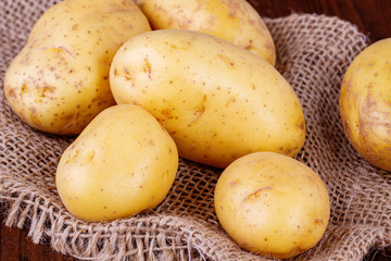 Surowe ziemniaki. Ziemniaki ze skorka na kuchennym stole. Worek z ziemniakami.  - obrazy, fototapety, plakaty