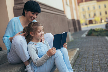 mother and daughter outdoor reading book
