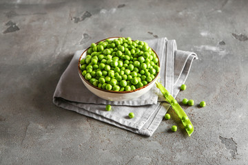 Bowl with tasty fresh peas on grunge background
