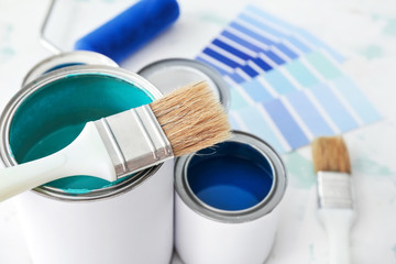 Cans of paint with brush on table, closeup - obrazy, fototapety, plakaty