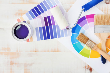 Can of paint with supplies and palette samples on light background