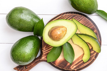 Board with fresh ripe avocados on white wooden background