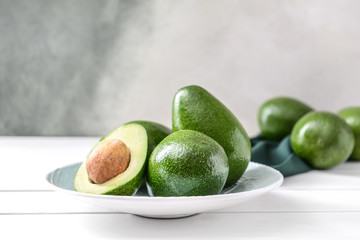 Plate with fresh ripe avocados on white table