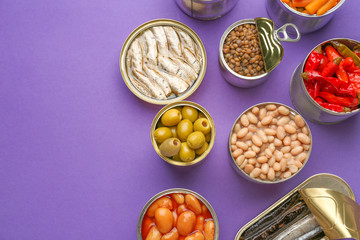 Tin cans with different food on color background