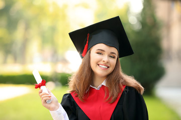 Happy young woman with diploma on graduation day