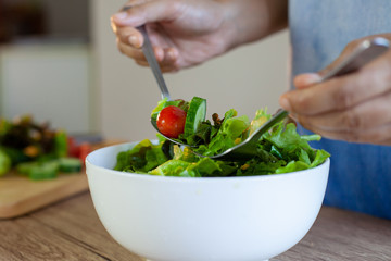 Asian woman mixing  fresh vegetable salad ingredients in the kitchen