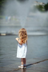 Little cute girl walking near the fountain, outdoor