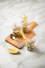 Norddeutscher Friesischer Nordseekrabben Salat Glas Becher mit Gurken, Radieschen, Zwiebeln, Dill und Zitronen auf Holz Brett und Marmor Tisch