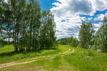 Fototapeta na wymiar A winding dirt road by the river on a sunny summer day.