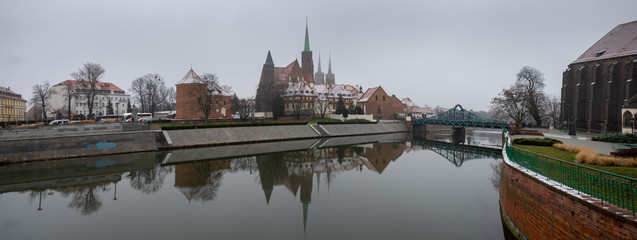 Panoramic view of the Cathedral of St. John the Baptist reflected in Oder river at cold snowy day. Ostrow Tumski district. Wroclaw. Poland