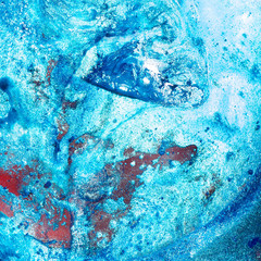 Macro shot suspension of particles in a colored emulsion over backlit background