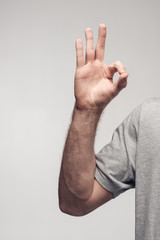 cropped view of man showing okay sign isolated on grey, human emotion and expression concept