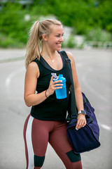 Fitness lifestyle. Athletic young woman drinks water from a bottle after a workout. Training at the stadium. Healthy lifestyle concept