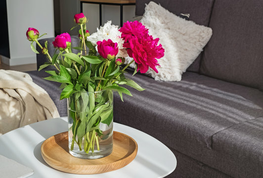 Beautiful peonies in the vase standing on the small table in the modern design living room
